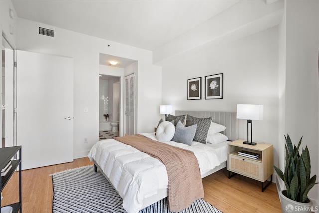 bedroom with a closet, connected bathroom, and light hardwood / wood-style flooring