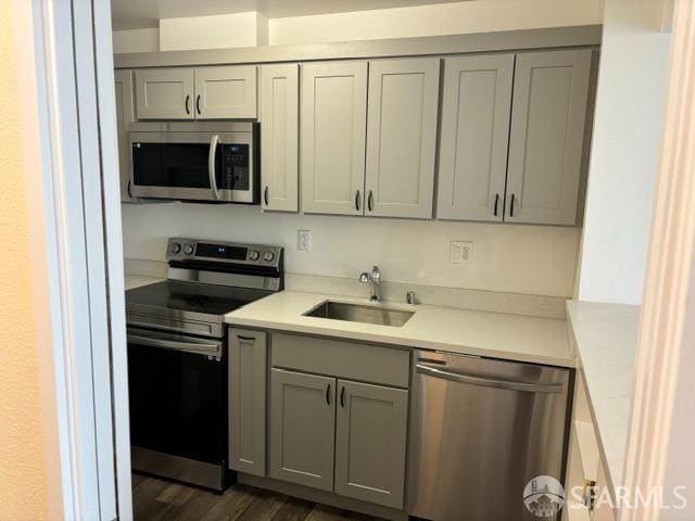 kitchen with gray cabinets, sink, stainless steel appliances, and dark hardwood / wood-style flooring