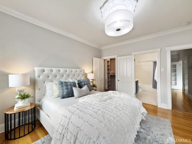 bedroom with hardwood / wood-style floors, crown molding, a walk in closet, and a closet