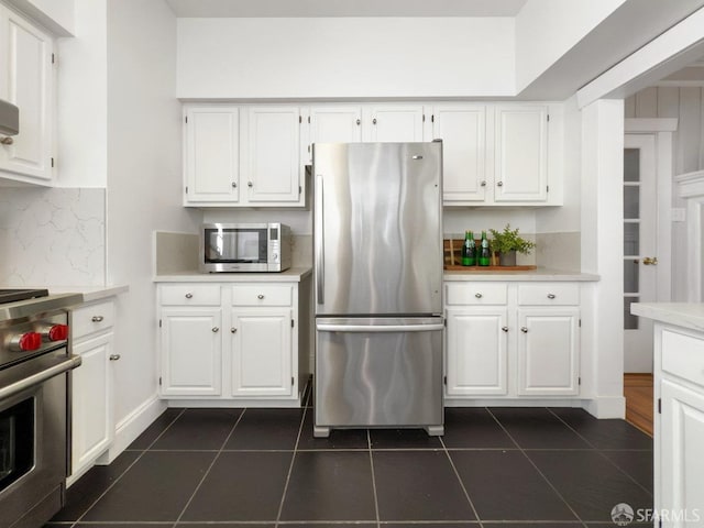 kitchen featuring stainless steel appliances, dark tile patterned floors, and white cabinets