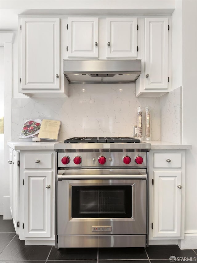 kitchen featuring white cabinetry, extractor fan, luxury stove, and dark tile patterned flooring