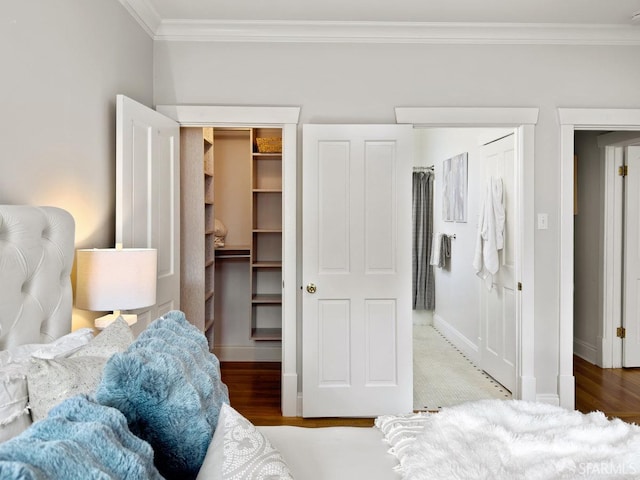 bedroom with crown molding, hardwood / wood-style flooring, and a spacious closet