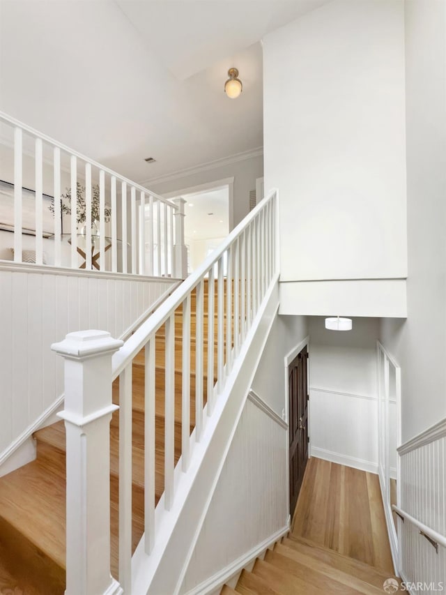 stairway with hardwood / wood-style flooring and ornamental molding