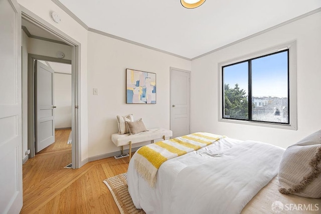 bedroom with visible vents, baseboards, ornamental molding, and light wood finished floors