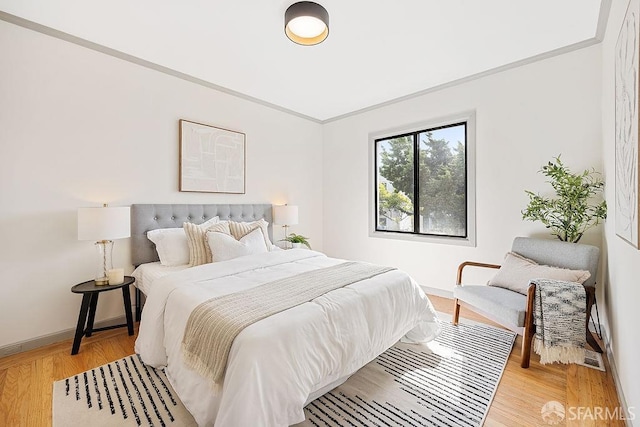 bedroom featuring light wood-style flooring, baseboards, and ornamental molding