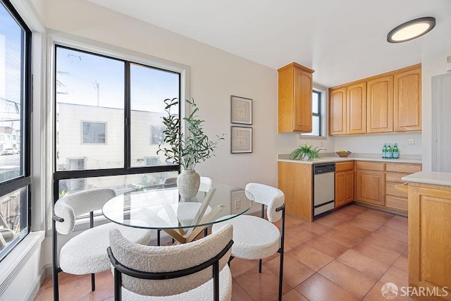 kitchen featuring light tile patterned floors, light brown cabinets, light countertops, and stainless steel dishwasher