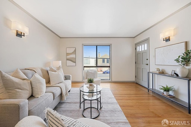 living area with crown molding, plenty of natural light, baseboards, and light wood finished floors