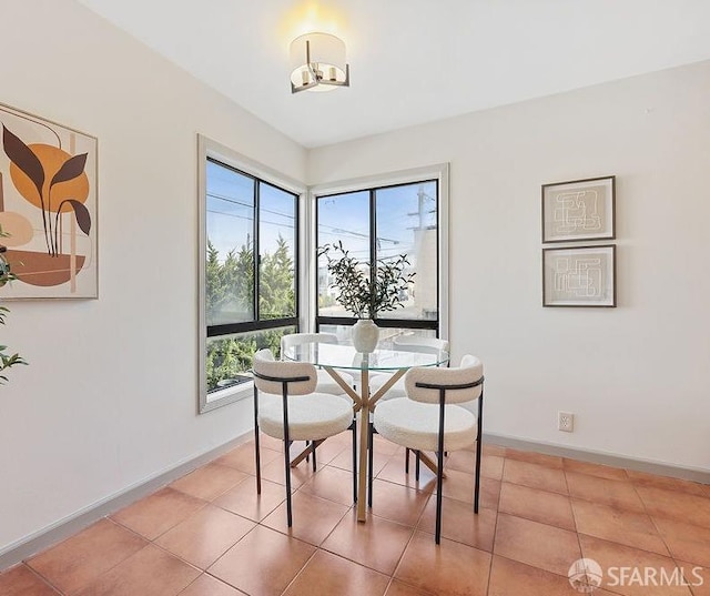 dining area with light tile patterned flooring, an inviting chandelier, and baseboards