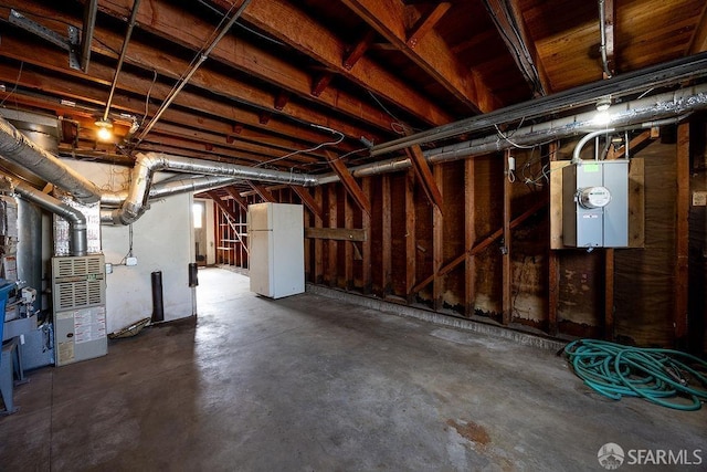 unfinished basement with heating unit and freestanding refrigerator