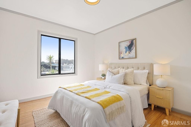 bedroom with light wood-type flooring, baseboards, and ornamental molding