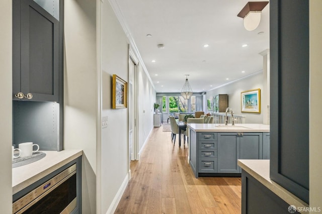 kitchen featuring gray cabinets, light hardwood / wood-style floors, crown molding, and sink