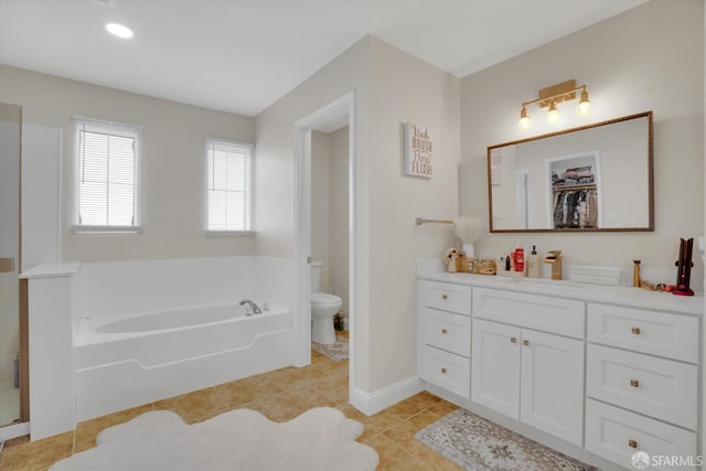 full bathroom with a garden tub, toilet, vanity, baseboards, and tile patterned floors