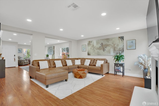 living area featuring light wood finished floors, a fireplace, visible vents, and recessed lighting