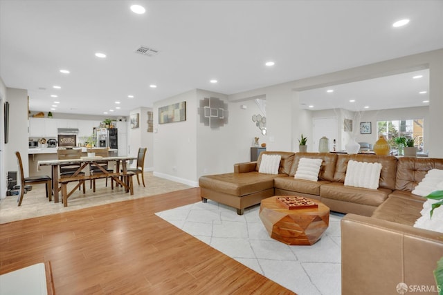 living area featuring baseboards, light wood-style flooring, visible vents, and recessed lighting