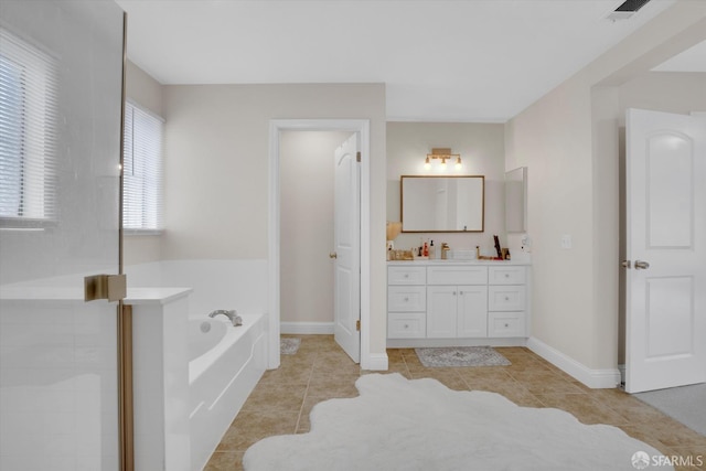 bathroom with tile patterned flooring, vanity, baseboards, and a bath