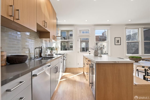 kitchen with a kitchen island, dishwasher, sink, backsplash, and light hardwood / wood-style flooring