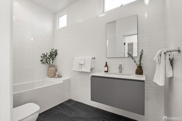 bathroom with toilet, tile walls, vanity, a bathtub, and tile patterned flooring