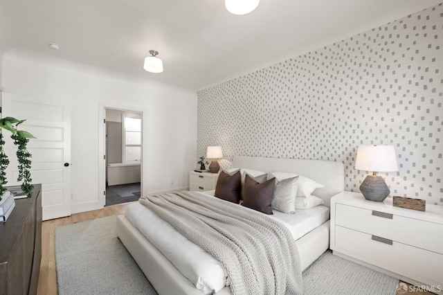 bedroom featuring light hardwood / wood-style floors and ensuite bath