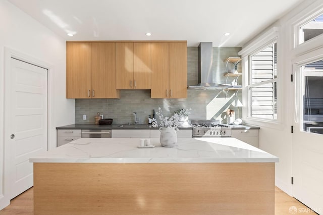 kitchen featuring sink, wall chimney range hood, dishwasher, a center island, and decorative backsplash