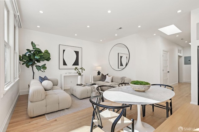 living room featuring light hardwood / wood-style flooring and a skylight