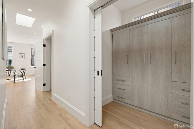 corridor featuring a skylight and light hardwood / wood-style flooring