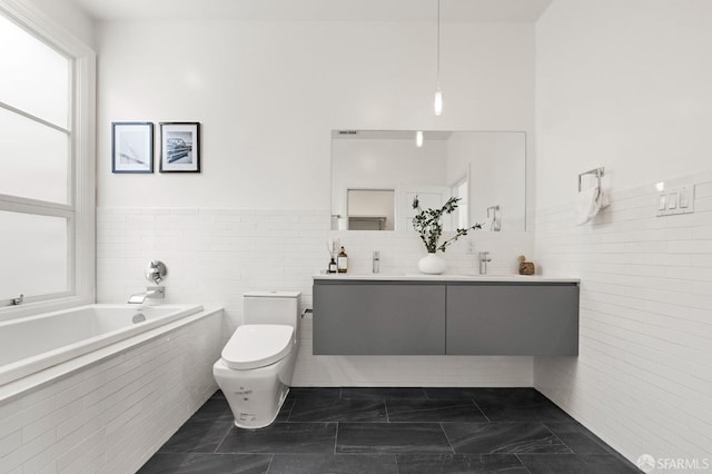 bathroom with vanity, toilet, tile walls, and tiled tub