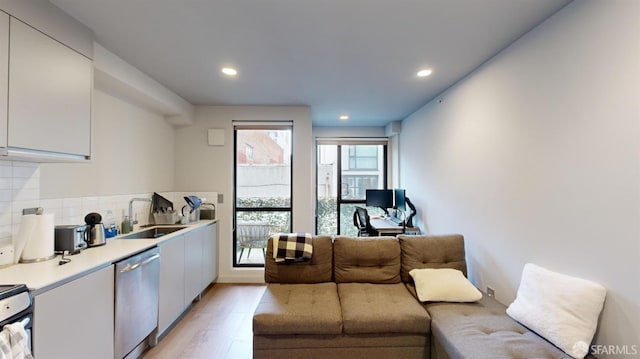 kitchen with sink, white cabinetry, dishwasher, light wood-type flooring, and decorative backsplash