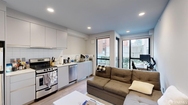 kitchen featuring white cabinets, tasteful backsplash, stainless steel appliances, light hardwood / wood-style flooring, and sink