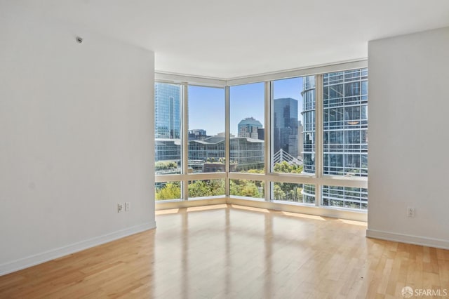 301 Mission St Unit 16H, San Francisco, CA 94105 - spare room featuring a wall of windows, healthy amount of natural light, a view of skyline, and wood finished floors