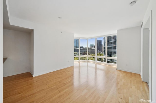 301 Mission St Unit 16H, San Francisco, CA 94105 - unfurnished room with a smoke detector, a wall of windows, light wood-style flooring, and a view of city