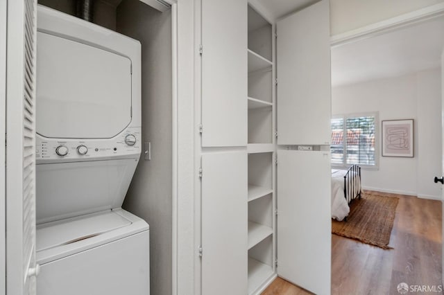 clothes washing area with stacked washer and dryer and light wood-type flooring