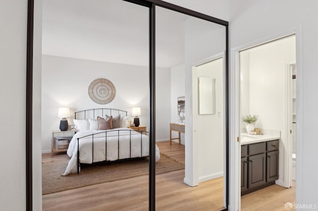 bedroom featuring ensuite bathroom and light hardwood / wood-style flooring