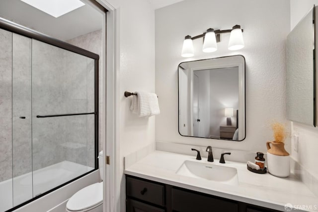 full bathroom with a skylight, bath / shower combo with glass door, vanity, and toilet