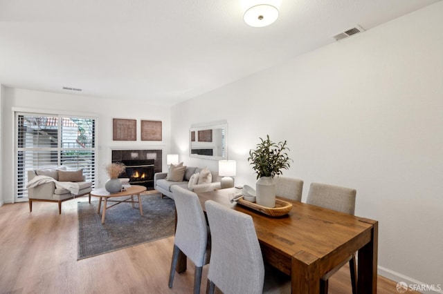 dining room with a fireplace and light hardwood / wood-style floors