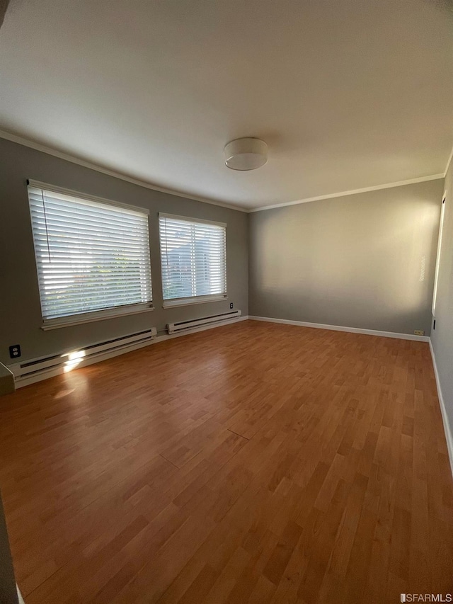 spare room featuring ornamental molding, hardwood / wood-style floors, and a baseboard heating unit