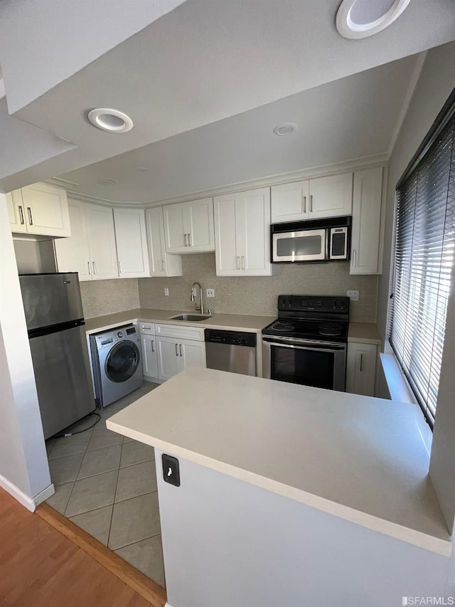 kitchen with light hardwood / wood-style floors, appliances with stainless steel finishes, washer / clothes dryer, and white cabinets