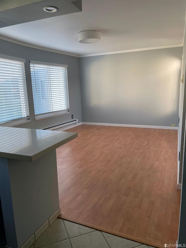 empty room featuring a baseboard radiator, crown molding, and light wood-type flooring