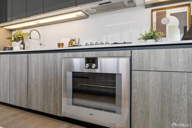 338 Main St Unit 19G, San Francisco, CA 94105 - kitchen view of range hood, beverage cooler, light wood-style floors, and modern cabinets
