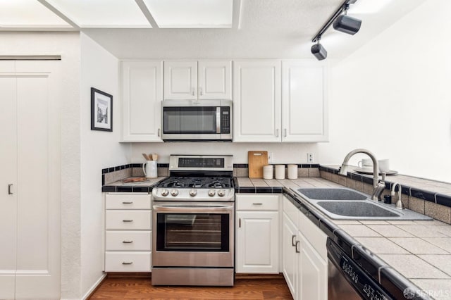 kitchen with white cabinetry, appliances with stainless steel finishes, sink, and tile countertops