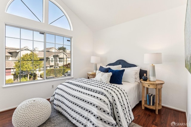 bedroom featuring multiple windows, lofted ceiling, and dark hardwood / wood-style flooring