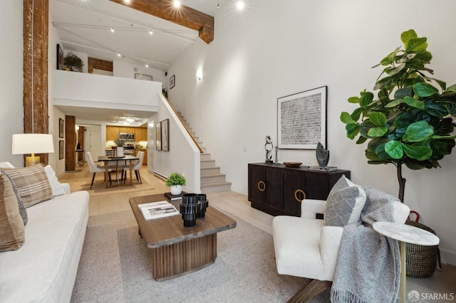 living room with beamed ceiling, light hardwood / wood-style floors, and a high ceiling