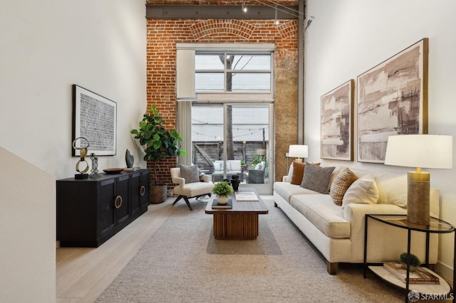 living room featuring a high ceiling, wood-type flooring, and a healthy amount of sunlight