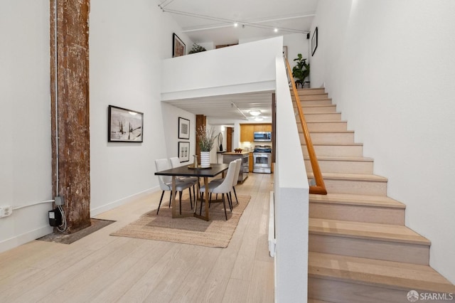 stairs with hardwood / wood-style floors and a high ceiling