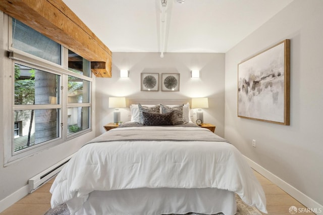 bedroom featuring beam ceiling, baseboard heating, and light hardwood / wood-style flooring