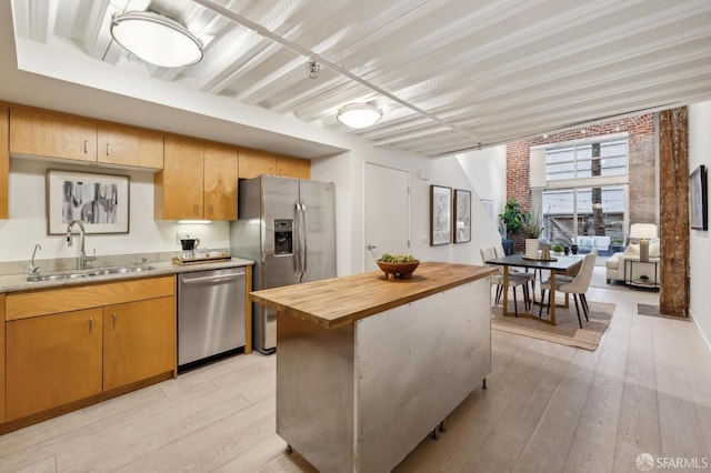 kitchen featuring sink, light hardwood / wood-style flooring, wooden counters, stainless steel appliances, and a kitchen island