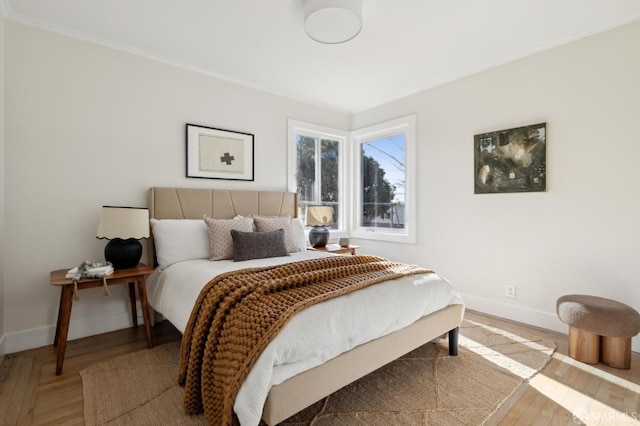 bedroom featuring baseboards, wood finished floors, and crown molding