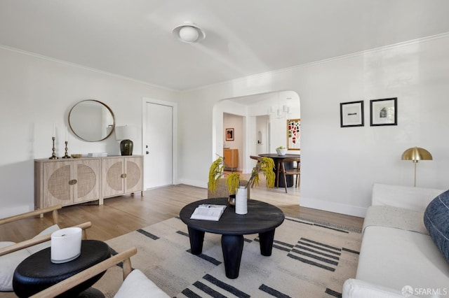 living room featuring ornamental molding, arched walkways, baseboards, and wood finished floors