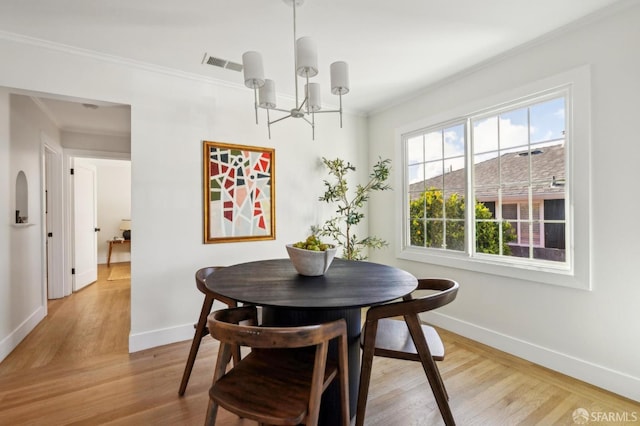 dining room featuring a notable chandelier, visible vents, baseboards, light wood finished floors, and crown molding