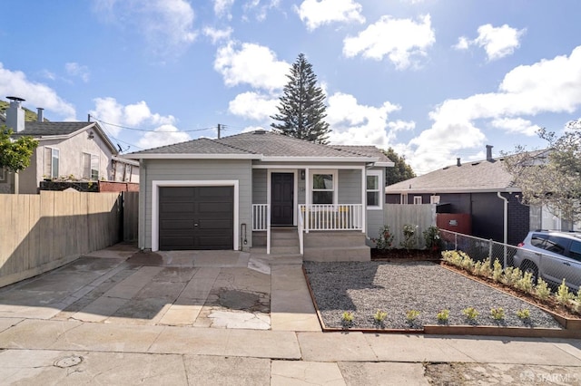 view of front of house featuring a porch, a shingled roof, concrete driveway, an attached garage, and fence