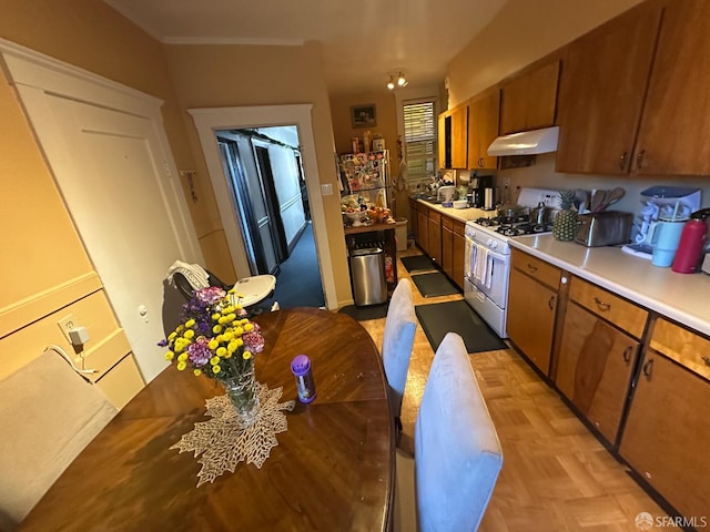 2773-2777 Bryant St, San Francisco, CA 94110 - kitchen featuring white gas stove, brown cabinets, light countertops, and under cabinet range hood